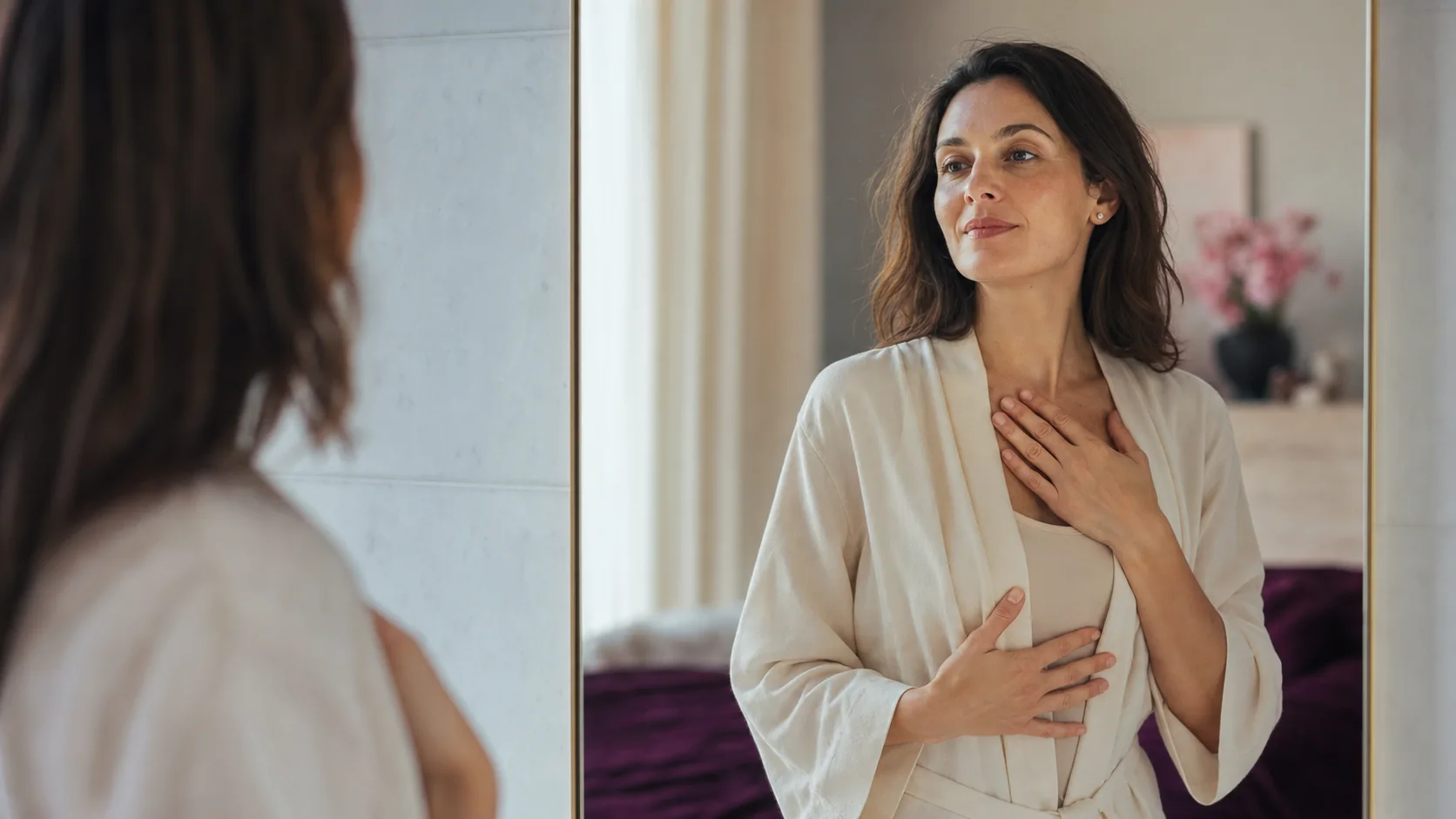 A woman in a robe stands calmly by a mirror during a private self-care moment.